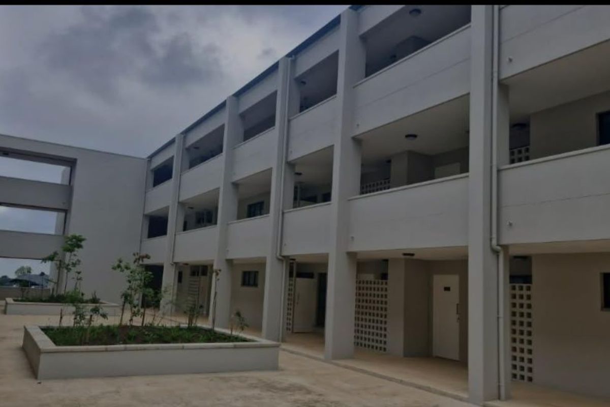 A view of the apartment complex exterior featuring multi-level balconies, concrete walkways, and integrated garden planters in the courtyard area.