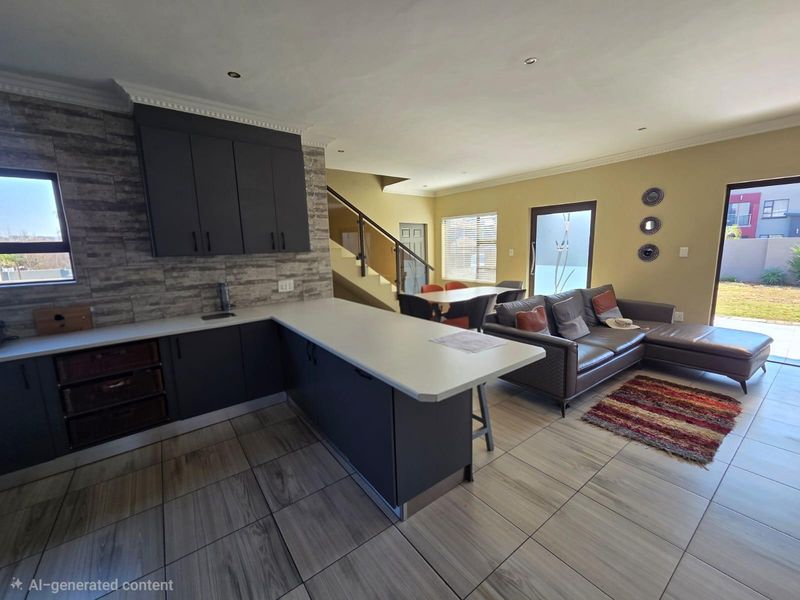 Spacious open-plan living area featuring a modern kitchen with dark cabinetry, stone countertops, tiled floors, and seamless access to the outdoor patio.