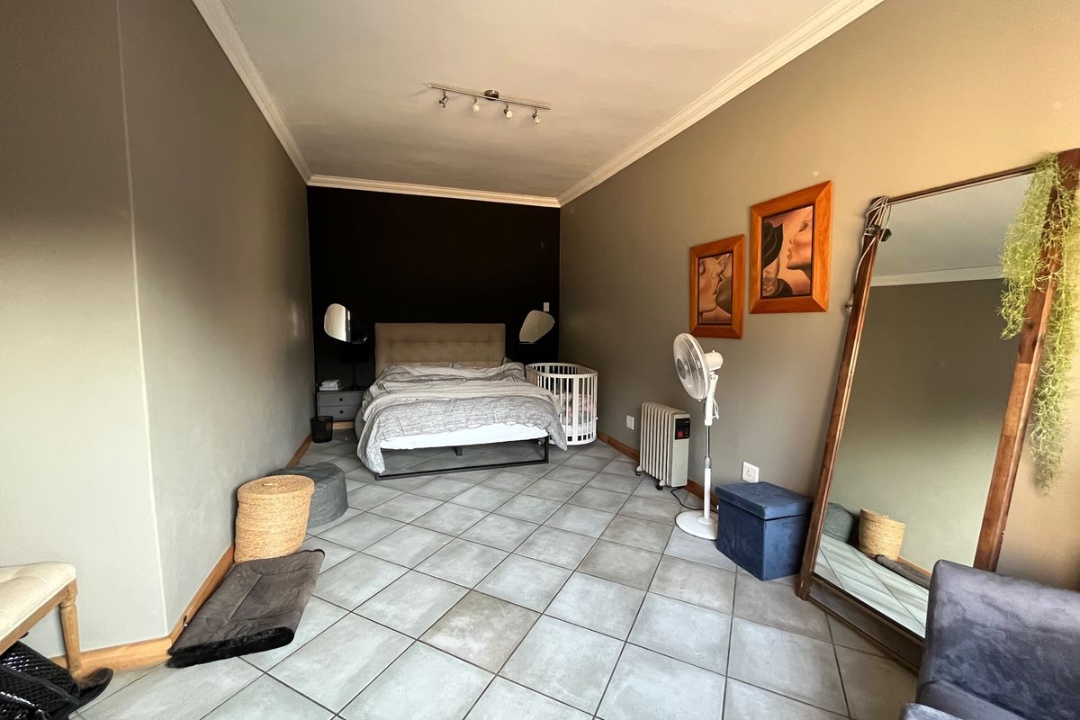 Spacious bedroom featuring neutral wall tones, tiled flooring, and ceiling coving, offering a versatile layout for various furniture arrangements.