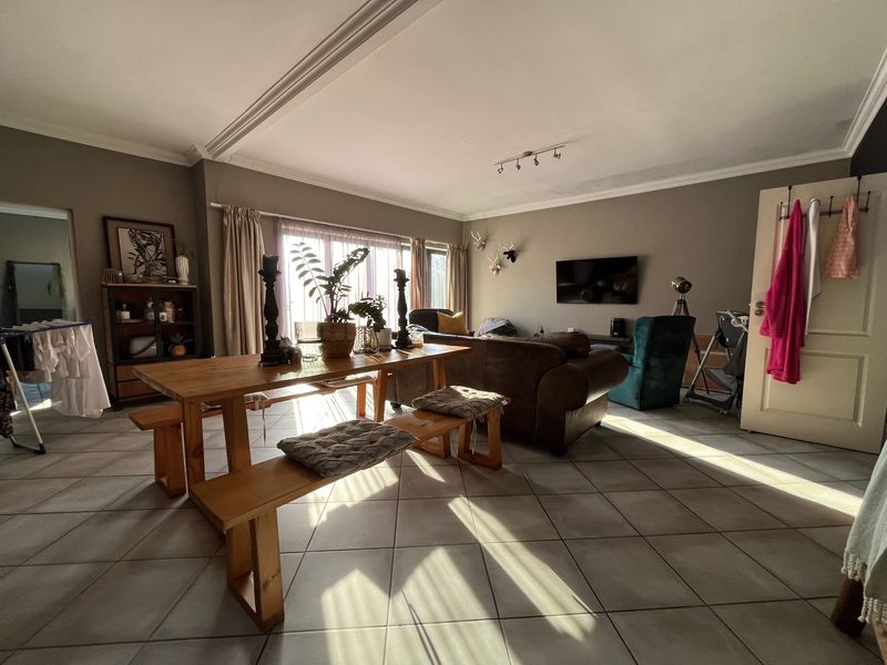 Spacious open-plan living and dining area featuring tiled flooring, ceiling cornicing, and large sliding doors providing natural light.