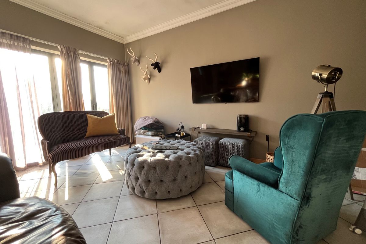 A living room featuring tiled flooring, crown molding, and large sliding glass doors that provide ample natural light.