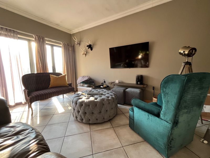 A living room featuring tiled flooring, crown molding, and large sliding glass doors that provide ample natural light.