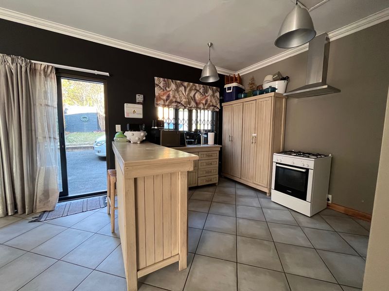 A functional kitchen featuring tiled flooring, a gas stove with extractor fan, built-in cabinetry, and a breakfast counter with direct access to the exterior.
