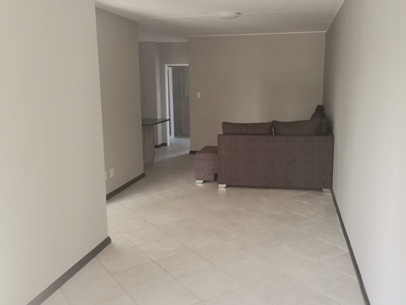 An open-plan living area featuring neutral wall tones and light-colored tiled flooring, providing a versatile space for layout customization.