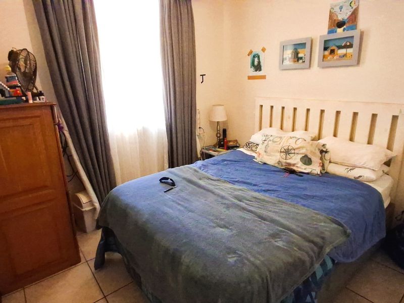 A functional bedroom featuring tiled flooring and window treatments, providing a comfortable space for rest.