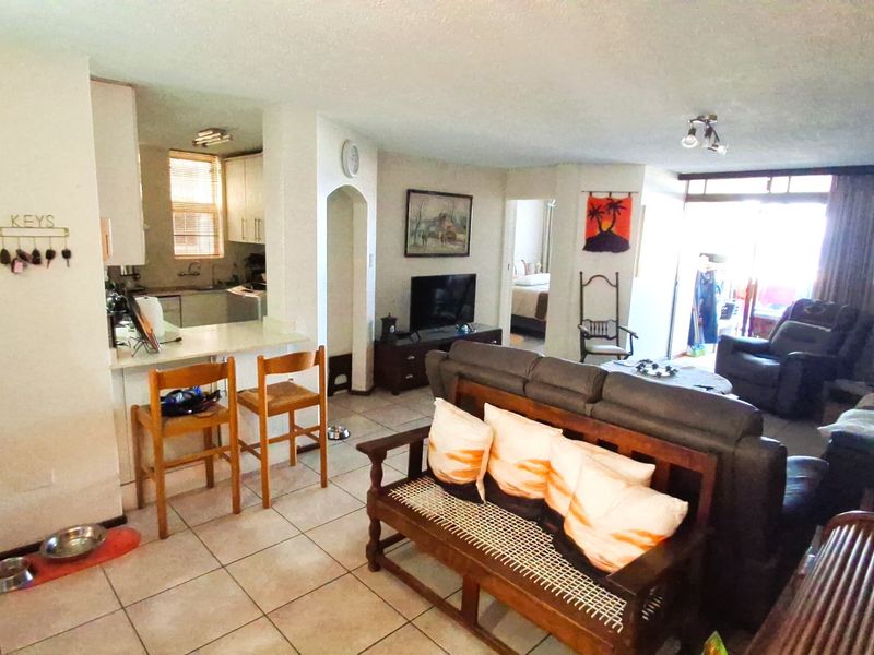 Open plan living area featuring a kitchen with breakfast bar, tiled flooring, and access to a balcony through sliding glass doors.