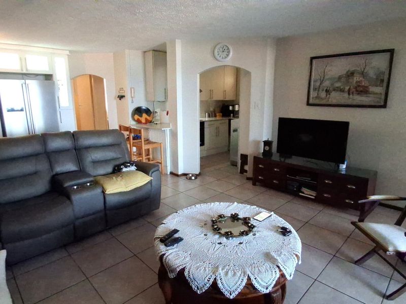 Open-plan living area featuring tiled flooring and an arched transition to the kitchen, providing a functional and connected layout for daily living.
