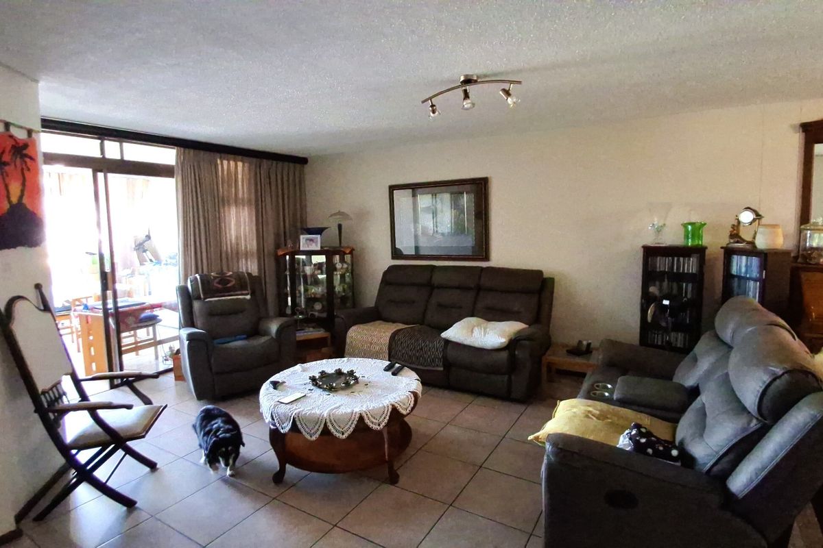 Spacious living room featuring ceramic floor tiles, ceiling track lighting, and large sliding glass doors providing access to the outdoor area.