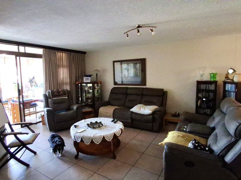 Spacious living room featuring ceramic floor tiles, ceiling track lighting, and large sliding glass doors providing access to the outdoor area.