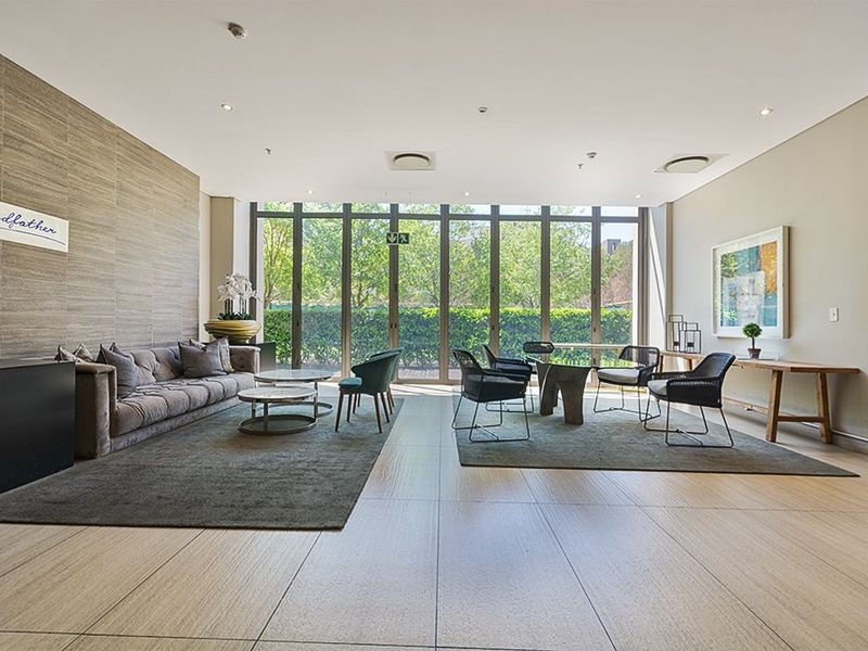 Spacious living area featuring large format floor tiles, a textured feature wall, and floor-to-ceiling glass doors providing ample natural light and garden views.