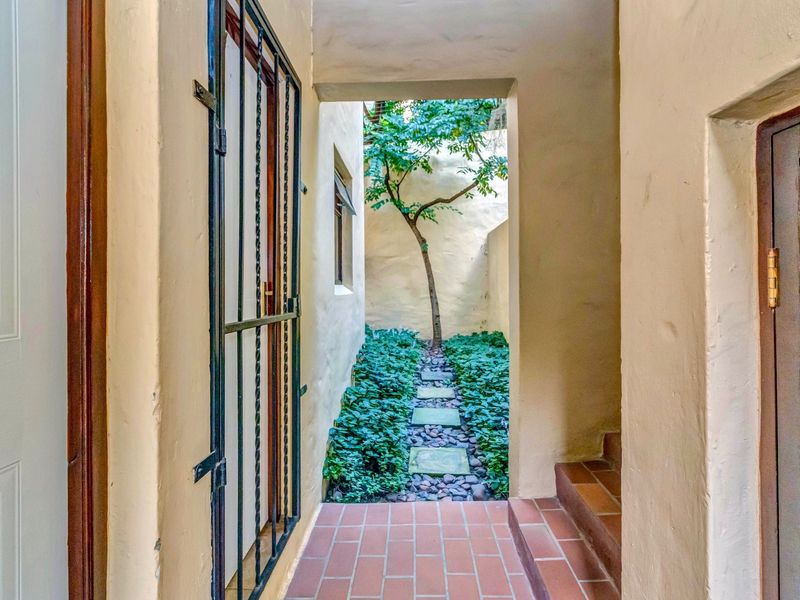 A private rear courtyard area featuring terracotta tiled flooring, a secure metal gate, and a landscaped garden path with stone pavers.