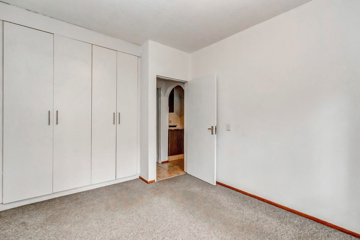 A clean, empty bedroom featuring neutral carpeting and ample built-in cupboard storage, providing a versatile space ready for personalization.