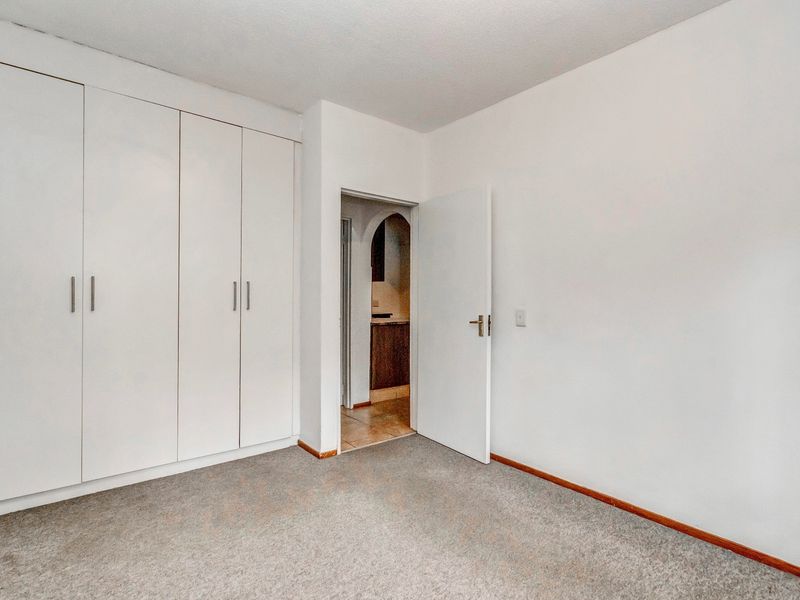 A clean, empty bedroom featuring neutral carpeting and ample built-in cupboard storage, providing a versatile space ready for personalization.