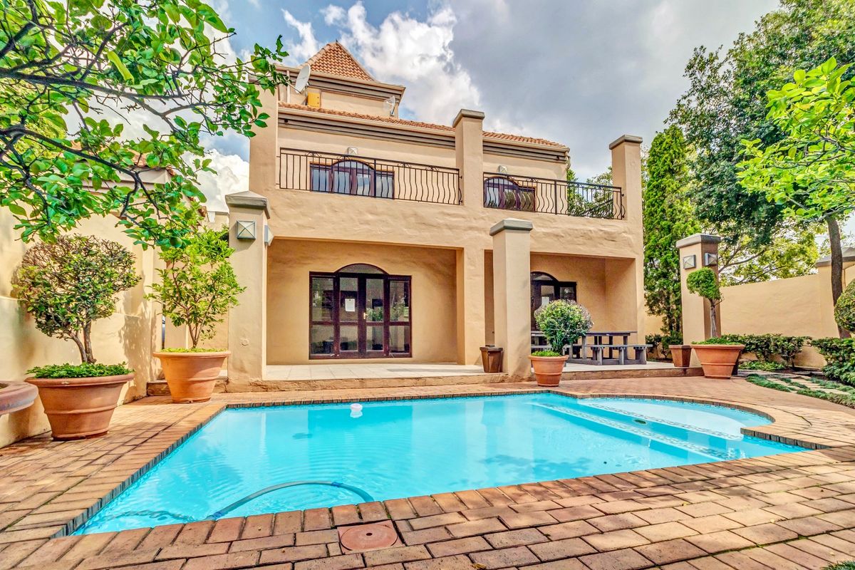 Rear view of the apartment featuring a private swimming pool, brick-paved patio area, and an upper-level balcony with wrought iron railings.
