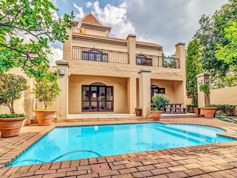 Rear view of the apartment featuring a private swimming pool, brick-paved patio area, and an upper-level balcony with wrought iron railings.