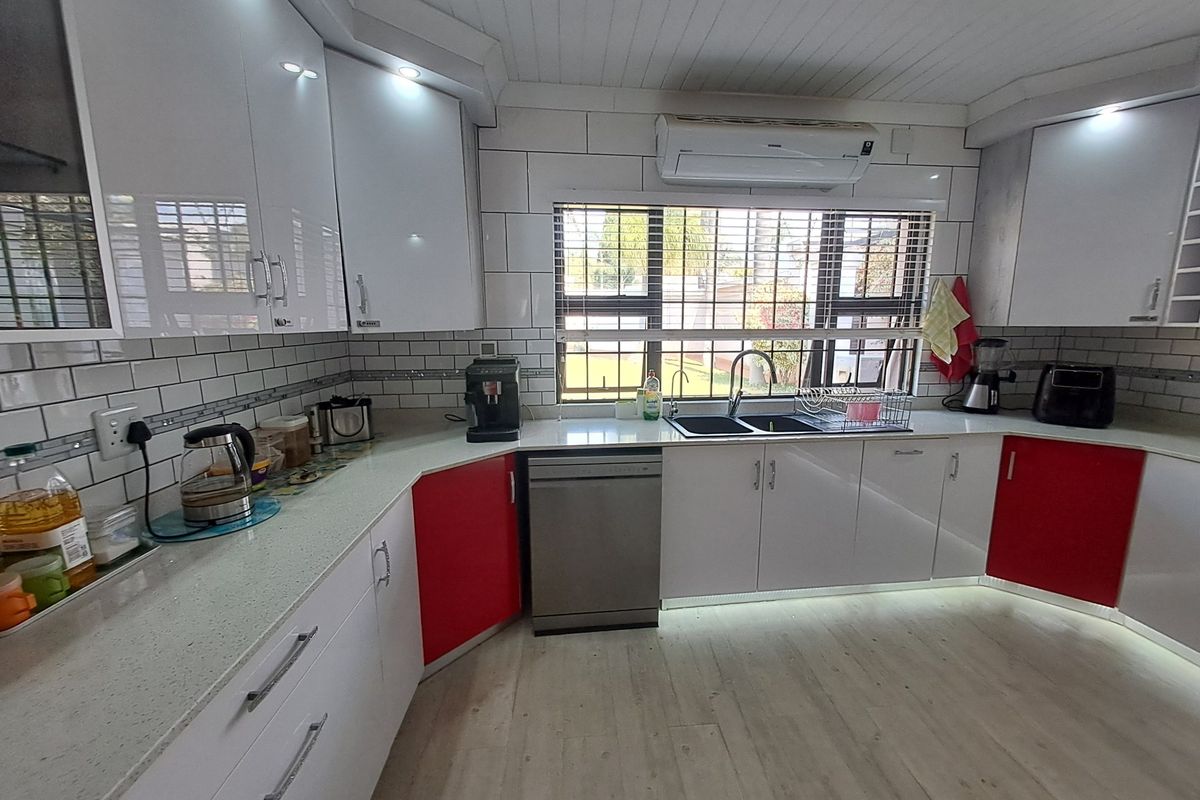 Modern kitchen featuring high-gloss cabinetry, stone countertops, subway tile backsplash, integrated dishwasher, and a split-system air conditioner.