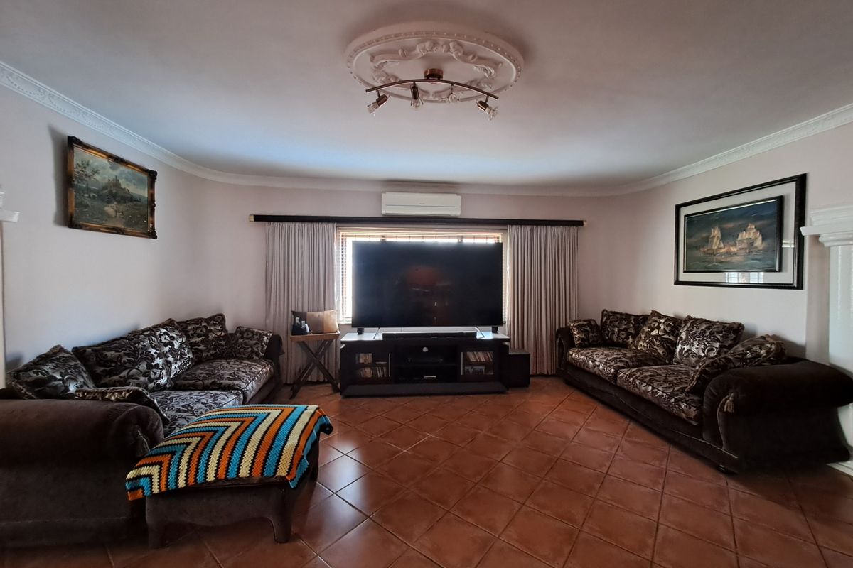 A spacious living room featuring ceramic tile flooring, decorative ceiling rose, and a wall-mounted split-system air conditioner.