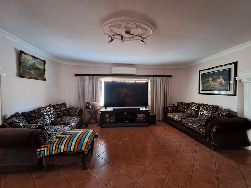 A spacious living room featuring ceramic tile flooring, decorative ceiling rose, and a wall-mounted split-system air conditioner.