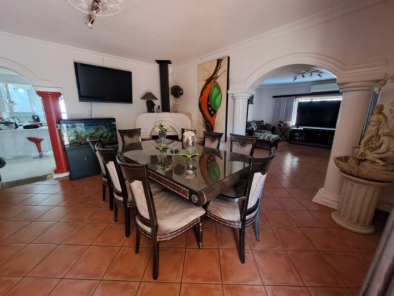 Spacious dining room featuring tiled flooring, decorative archways, and a central fireplace, connecting to adjacent living and kitchen areas.