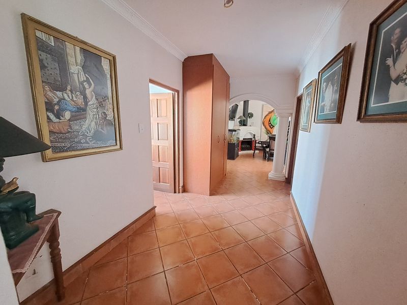 A tiled hallway featuring an archway leading to an adjacent living space and a built-in storage cupboard.