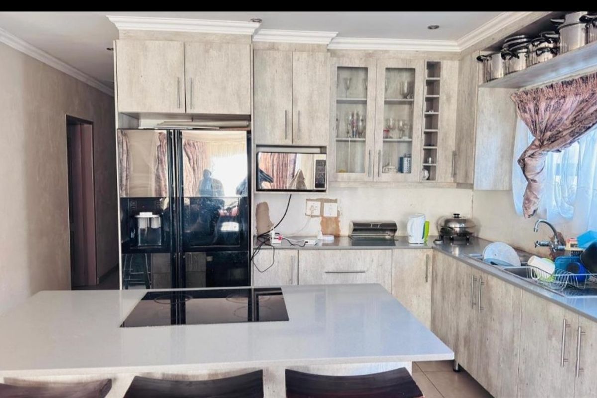 Kitchen featuring light wood-grain cabinetry, a central island with an integrated electric hob, and a stainless steel sink.
