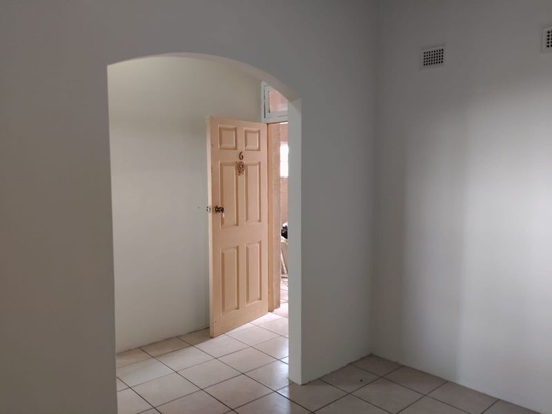 A clean, empty hallway featuring tiled flooring and an arched doorway leading to an adjacent room.