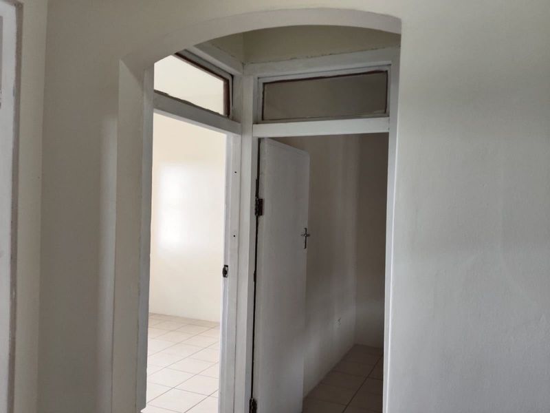 A view through an arched doorway into an empty room with tiled flooring and a transom window above the door frame.