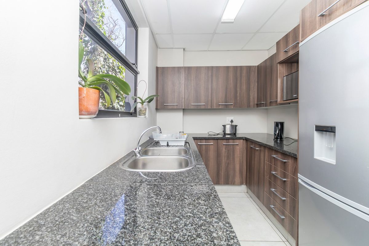 A clean and functional commercial kitchen featuring granite countertops, ample laminate cabinetry, and a double basin stainless steel sink.