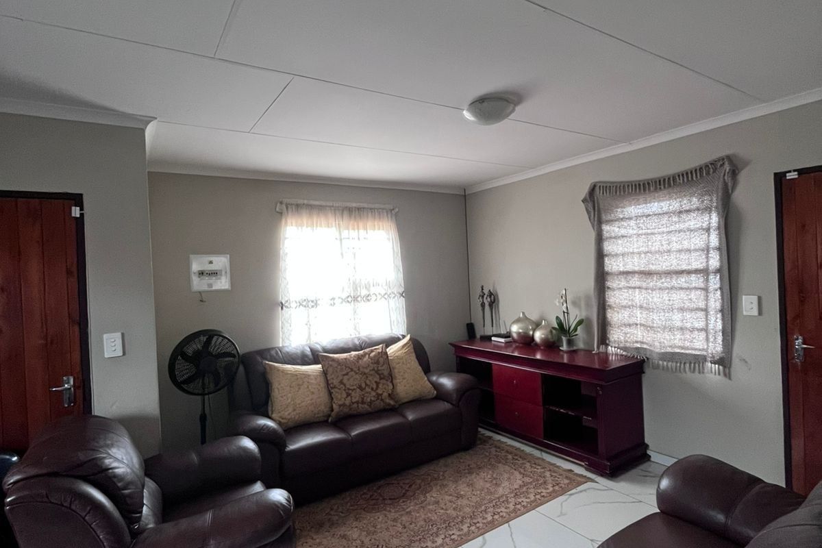 A living room featuring white marble-look floor tiles, neutral wall paint, and timber doors, providing a functional and well-maintained living space.
