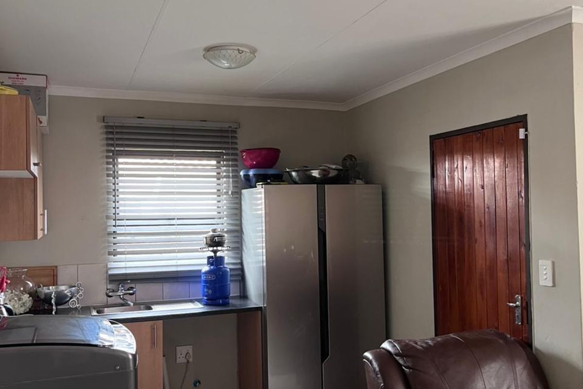 A functional kitchen area featuring tiled flooring, a single sink, and a wooden door, providing a practical space for daily tasks.