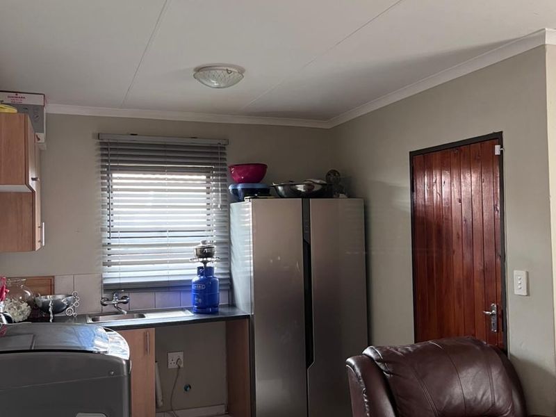 A functional kitchen area featuring tiled flooring, a single sink, and a wooden door, providing a practical space for daily tasks.