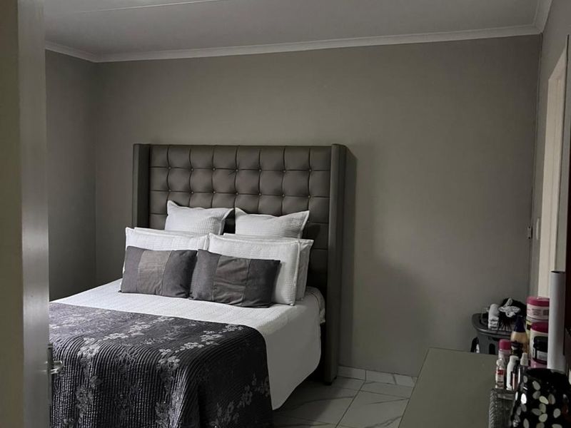 A well-maintained bedroom featuring neutral wall tones, modern marble-look floor tiles, and a central ceiling light fixture.