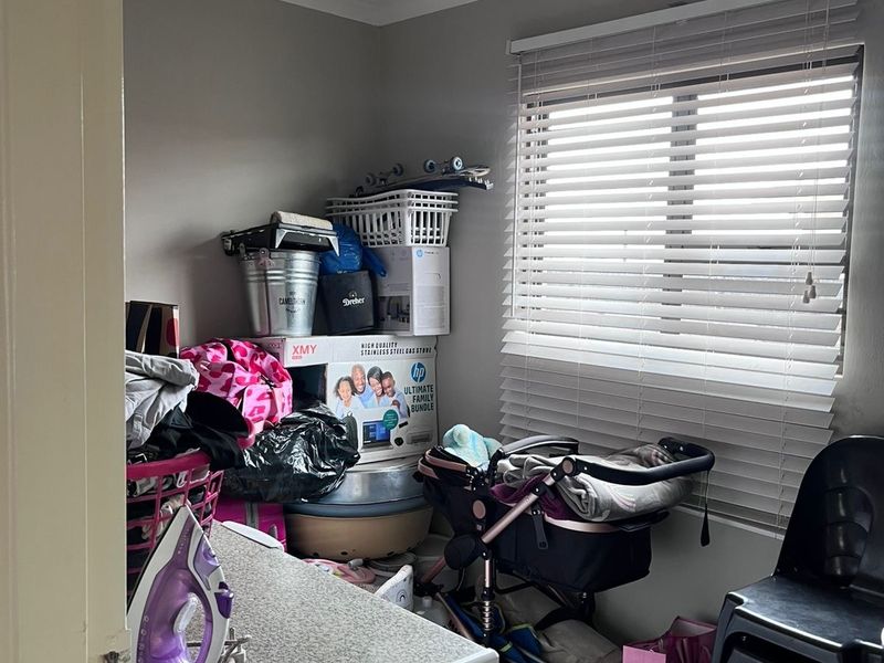 A functional utility space featuring tiled flooring, a window with venetian blinds, and a ceiling light fixture.