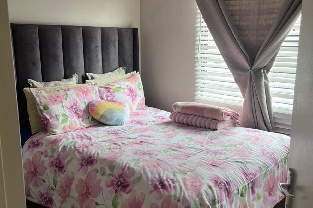 A cozy bedroom featuring tiled flooring and venetian blinds, providing a clean and functional space.