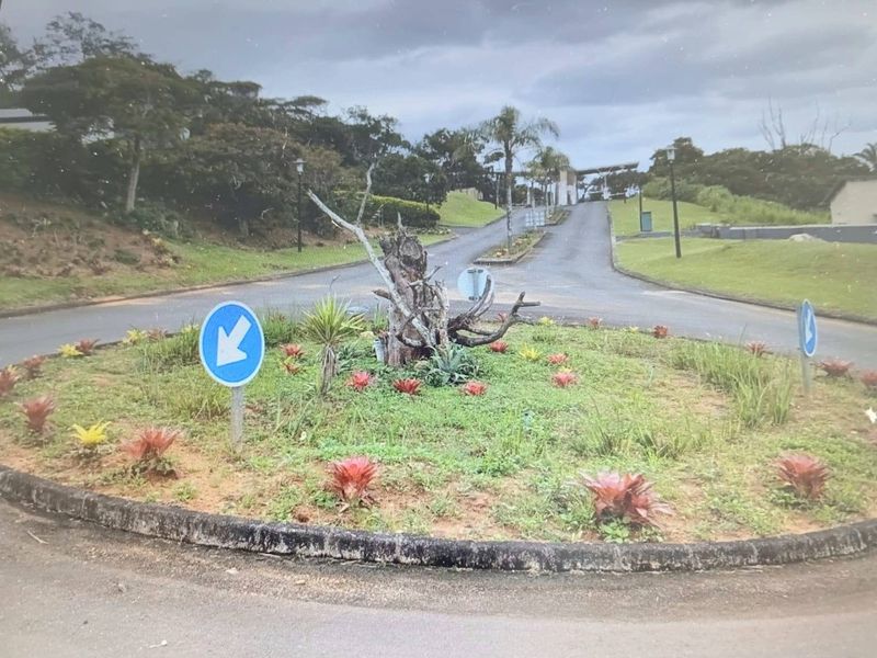 A view of the residential estate entrance featuring a landscaped roundabout and paved access roads.
