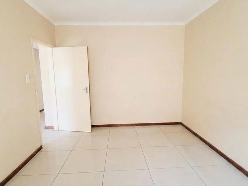 A clean, empty bedroom featuring neutral wall paint, tiled flooring, and simple architectural finishes, providing a blank canvas for personalization.