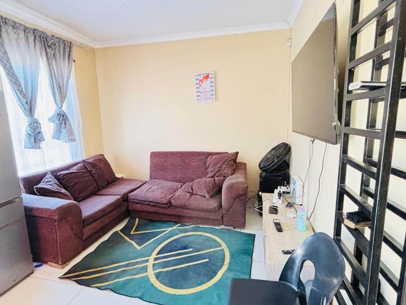 A compact living area featuring tiled flooring and coved ceiling details, providing a functional space for relaxation.