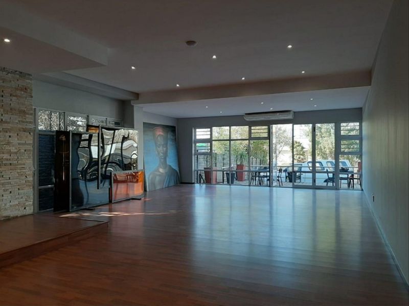 Spacious open-plan commercial area featuring timber flooring, a stone feature wall, recessed lighting, and large glass sliding doors providing ample natural light.