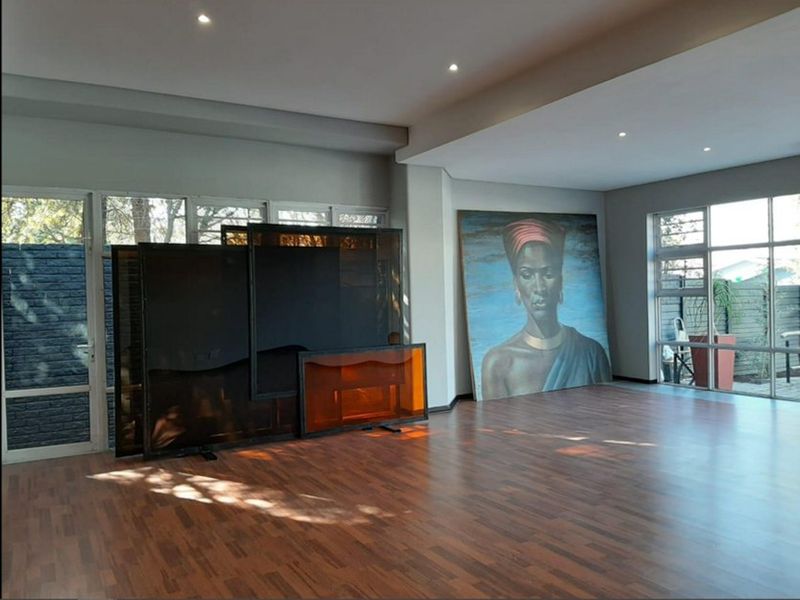 Spacious open-plan living area featuring modern laminate flooring, recessed downlighting, and large aluminium-framed windows providing ample natural light.