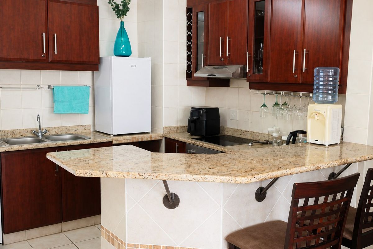 A functional kitchen featuring dark wood cabinetry, granite countertops, a breakfast bar, and integrated appliances, providing a practical layout for cooking and dining.