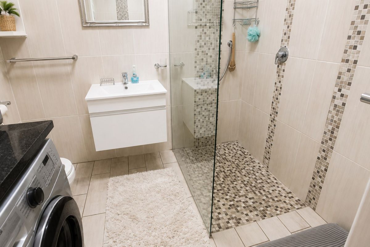 Modern bathroom featuring a wall-mounted vanity, a spacious walk-in shower with glass enclosure, and neutral ceramic tiling throughout.