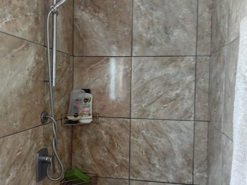 A shower enclosure featuring brown marble-effect wall tiles and a modern chrome shower fixture.