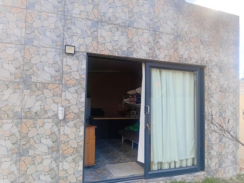 Exterior view of a rear wall featuring stone cladding, a sliding glass door, and an outdoor security light.
