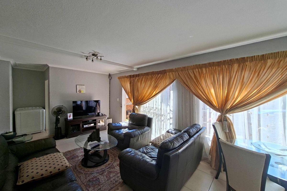A living room area featuring tiled flooring and a large sliding glass door that provides access to the exterior.