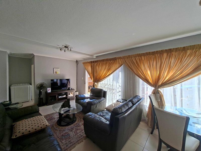 A living room area featuring tiled flooring and a large sliding glass door that provides access to the exterior.