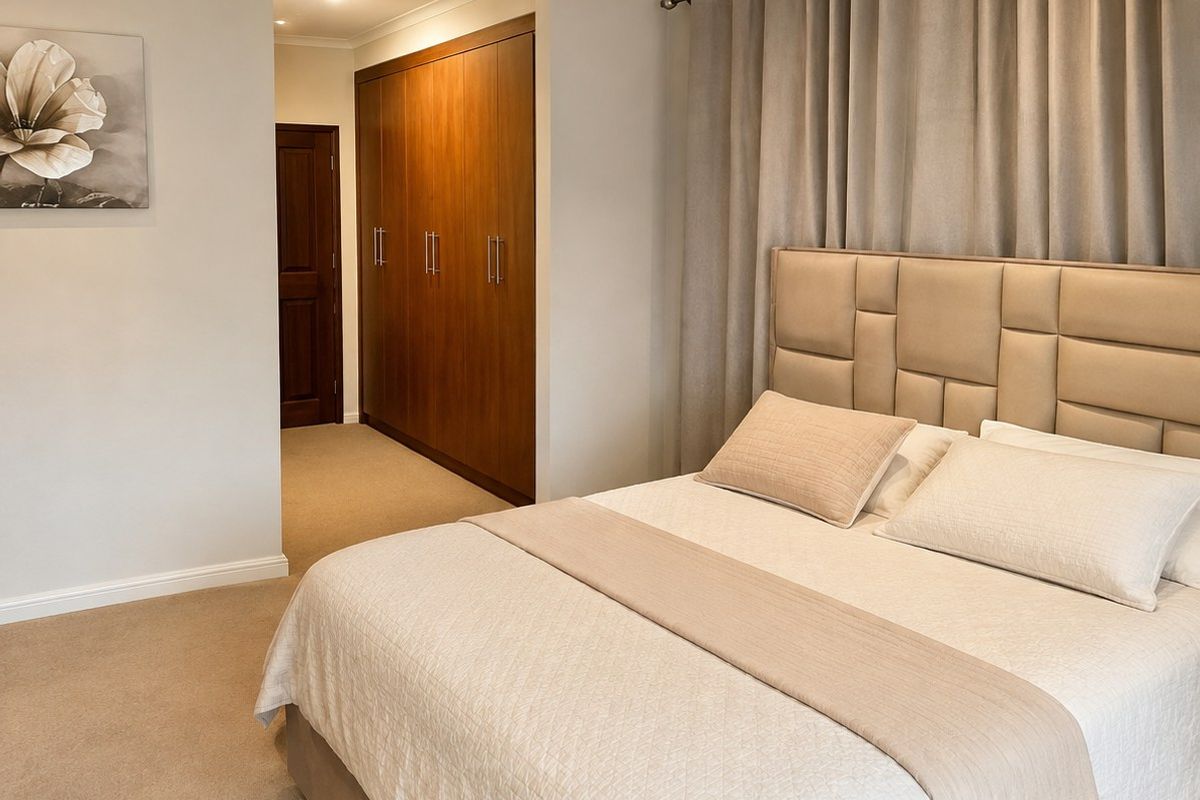 A well-maintained bedroom featuring neutral carpeting, recessed downlighting, and extensive built-in wooden cabinetry for storage.