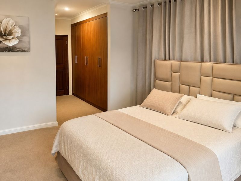A well-maintained bedroom featuring neutral carpeting, recessed downlighting, and extensive built-in wooden cabinetry for storage.