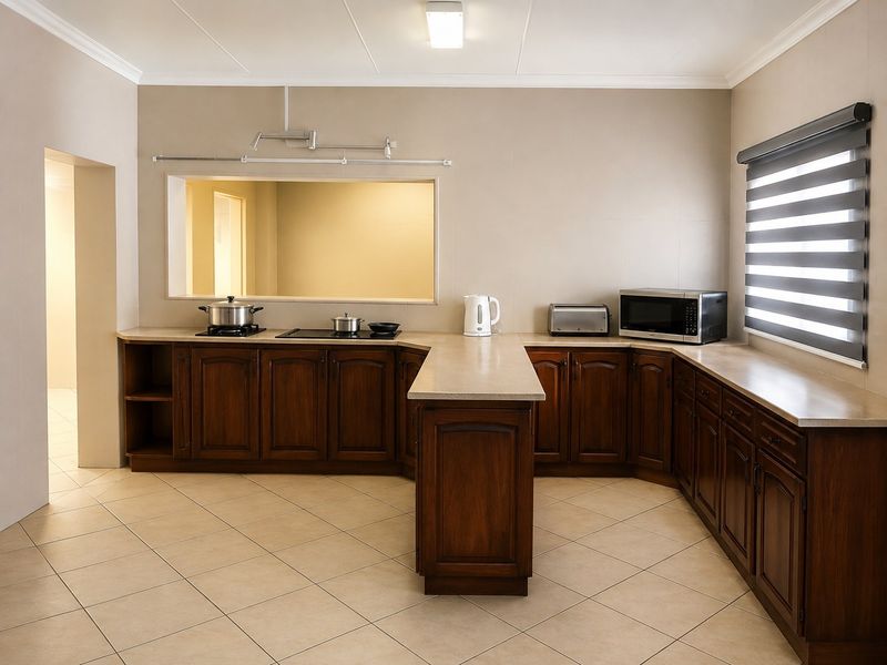 A well-maintained kitchen featuring dark wood cabinetry, stone countertops, ceramic tile flooring, and a convenient pass-through window to the adjacent room.