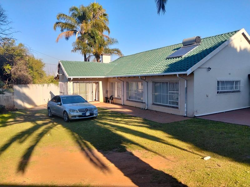Rear view of the house featuring a tiled roof with solar water heating, security bars on windows, and a paved patio area.