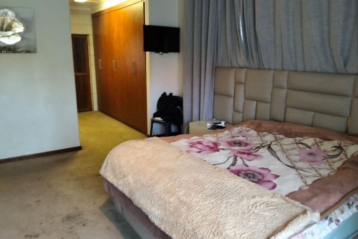 A bedroom featuring built-in wooden cupboards and carpeted flooring, requiring cosmetic updates to improve the overall condition and appeal.